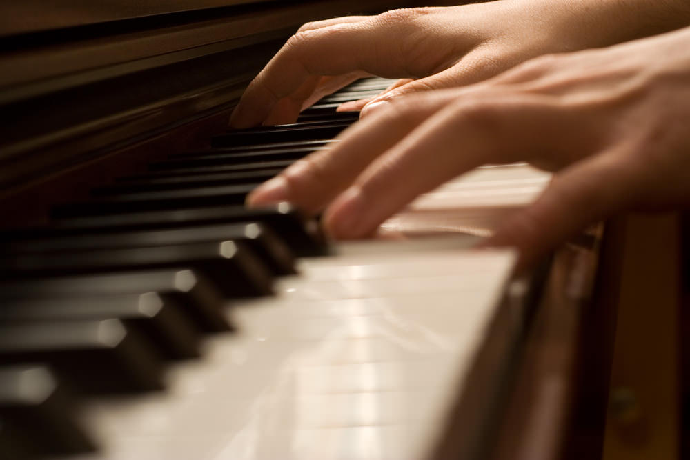 Hands playing a piano keyboard